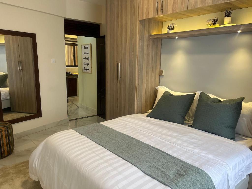um quarto com uma grande cama branca com almofadas azuis em The Nicoletta Apartment 104 em Kampala