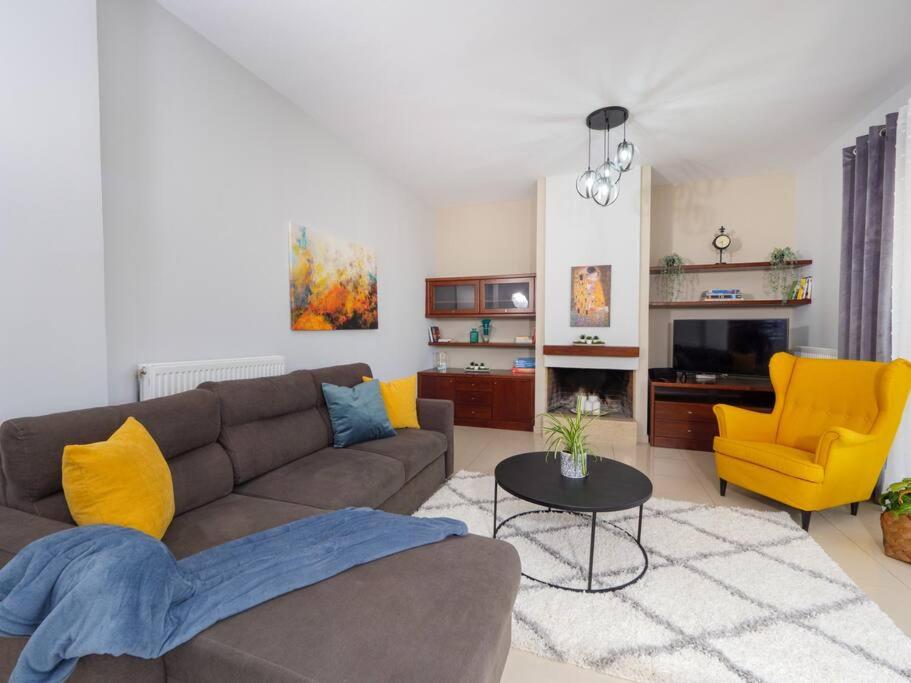 ein Wohnzimmer mit einem braunen Sofa und gelben Stühlen in der Unterkunft GPK Bright & Stylish 4BR - Central with Free Parking in Iraklio