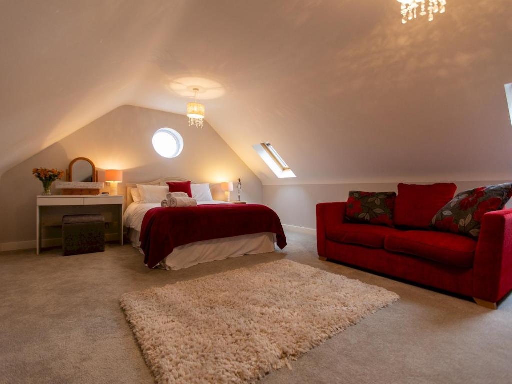 una camera con un letto e un divano rosso di Pass the Keys Superb space in the idyllic village of Loppington a Shrewsbury