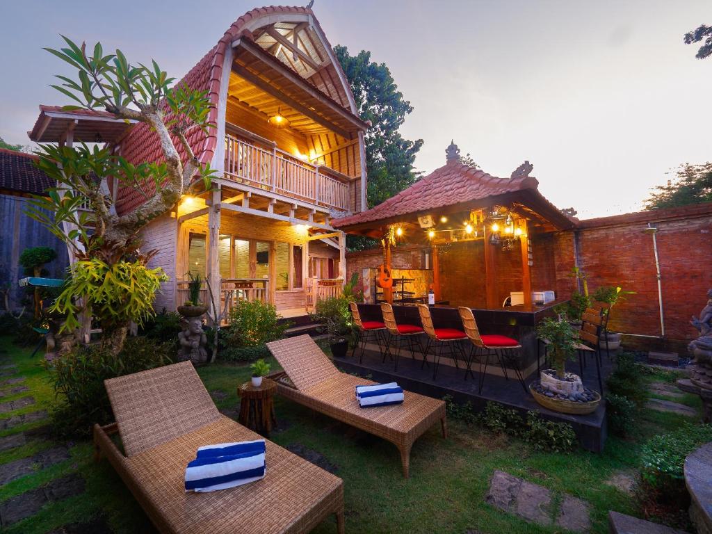 a house with chairs and tables in the yard at Wisnu Lumbung Uluwatu in Uluwatu