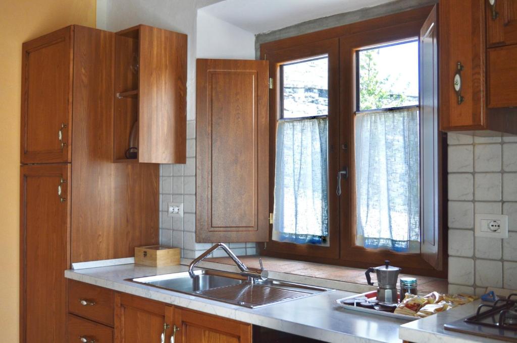 a kitchen with wooden cabinets and a sink and two windows at Agriturismo Vezzano in Chiusi della Verna