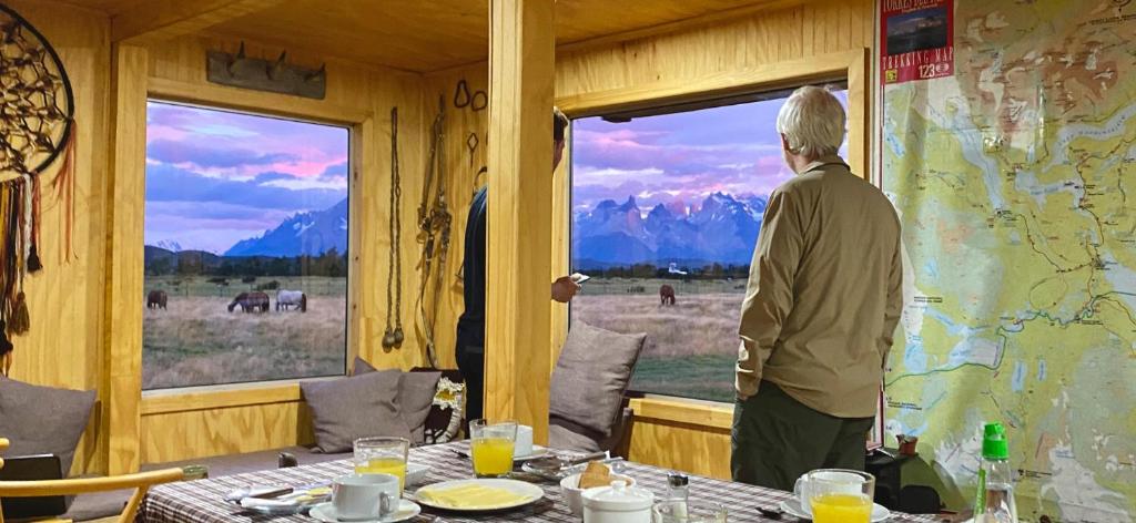 a man looking out of a window at a table at Vista al Paine - Refugio de Aventura in Torres del Paine