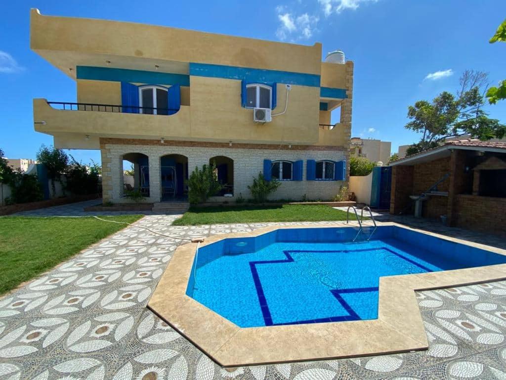 una casa con piscina frente a una casa en Blue House, en Alejandría