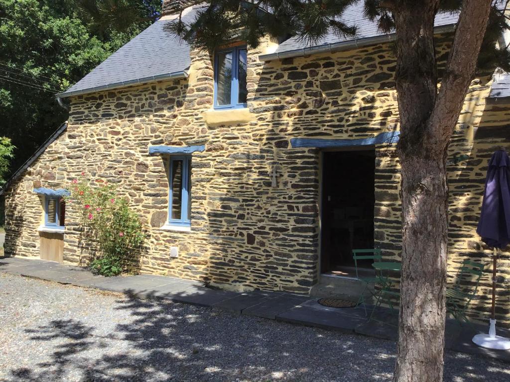 un edificio in pietra con una porta e un albero di Coucou cottage 