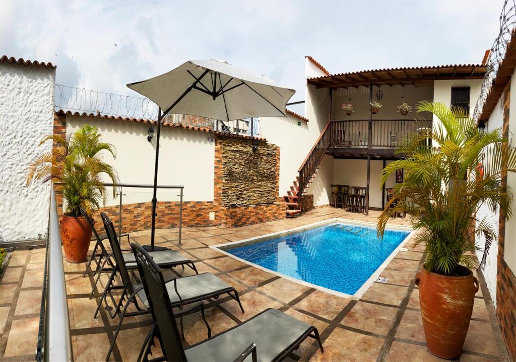 een patio met een zwembad, stoelen en een parasol bij Hotel Boutique Colonial Cartago in Cartago
