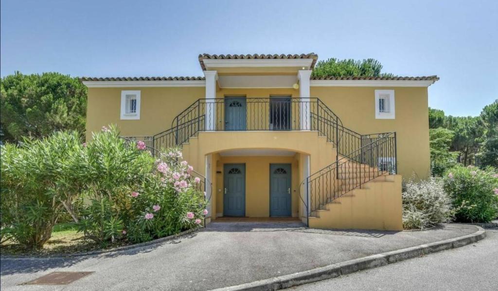 une maison jaune avec un escalier devant elle dans l'établissement Les Jardines d`Artemis (27), à Saint-Tropez