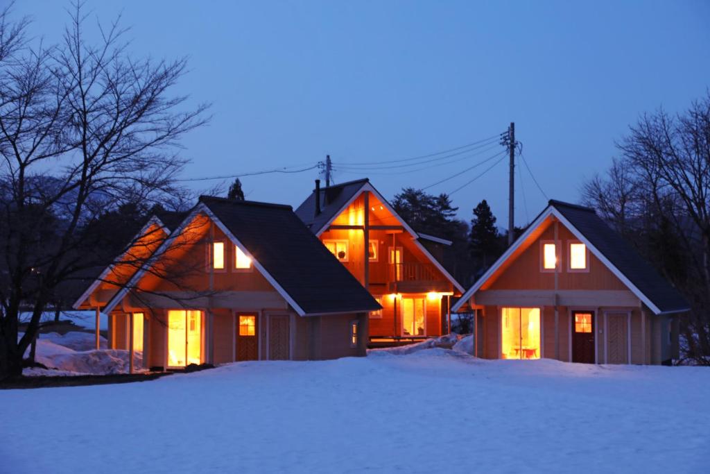 two houses with their lights on in the snow at Log Cottage 白馬KIITOS in Hakuba