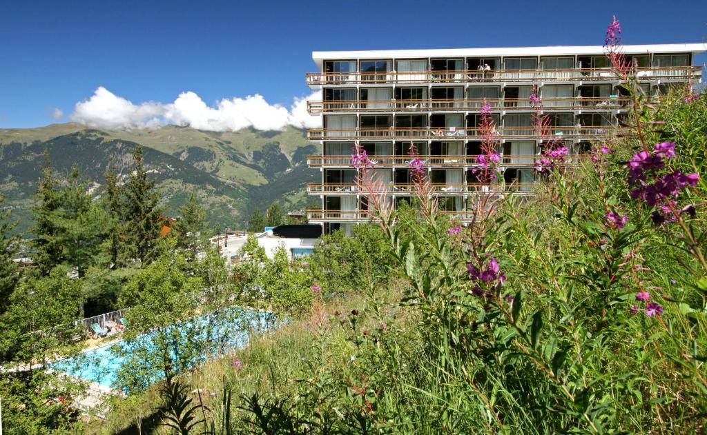 een gebouw bovenop een heuvel met bloemen bij Résidence Pierre & Vacances le Moriond in Courchevel