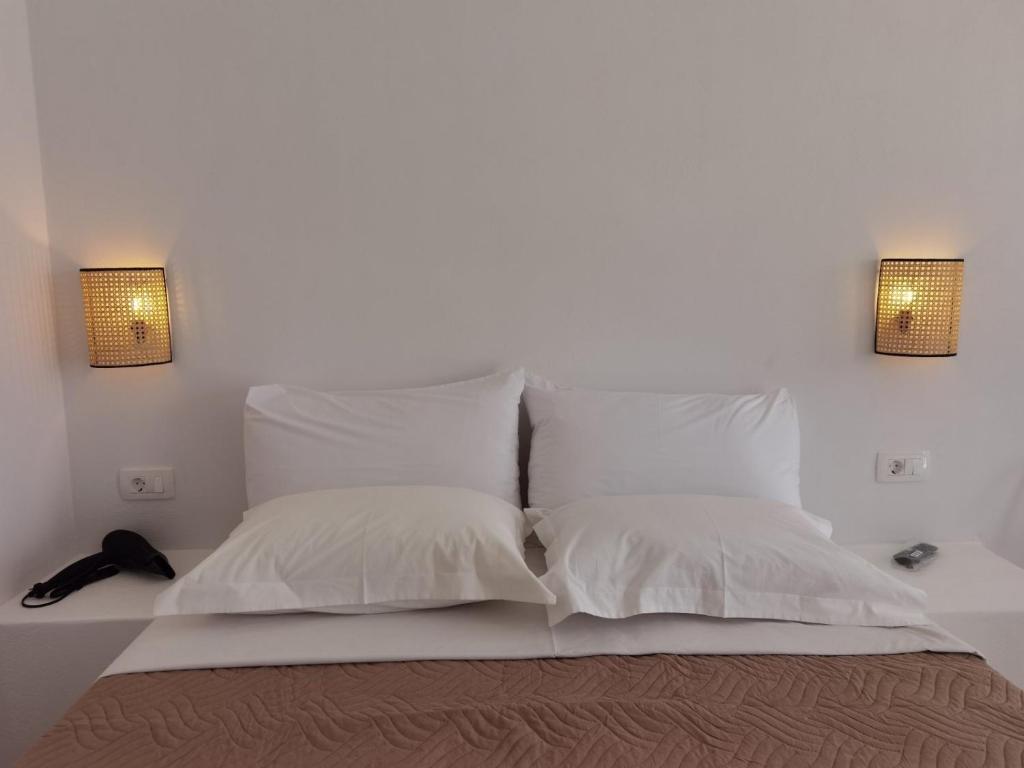 a white bed with two pillows and two lights on the wall at Villa Konstantinos in Perissa