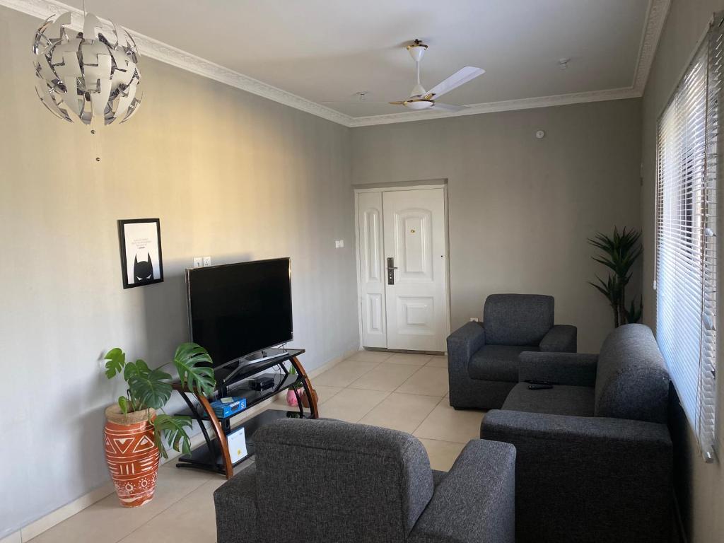 ein Wohnzimmer mit 2 Stühlen und einem TV in der Unterkunft Newly Built 2 bedroom En-suite Apt. in Accra