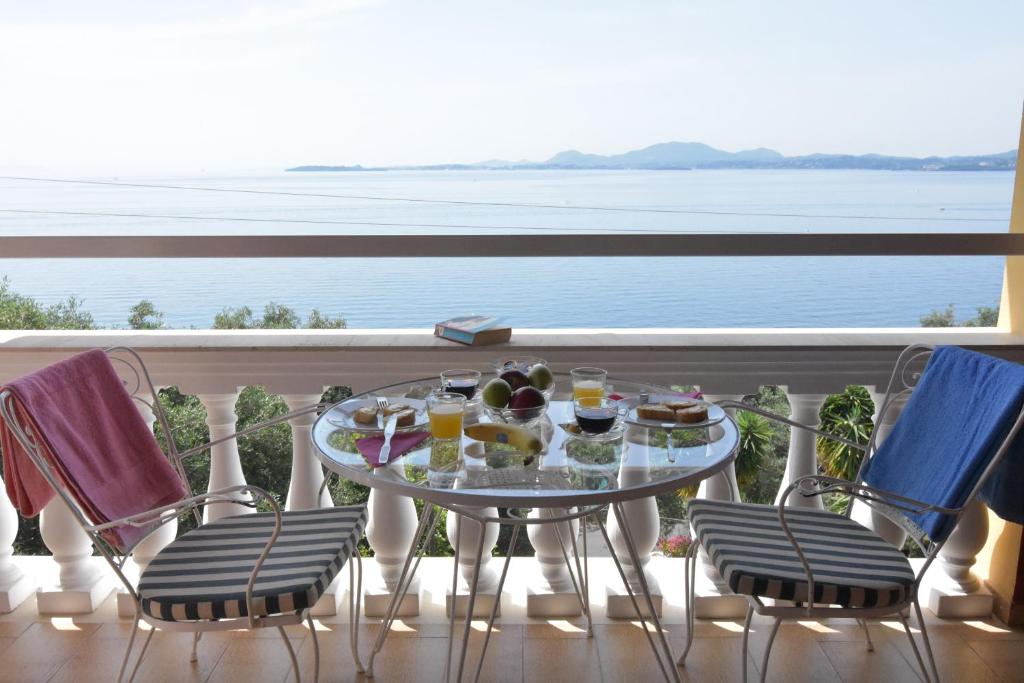 a table and chairs on a balcony with a view of the ocean at Baracunda Apartments in Barbati