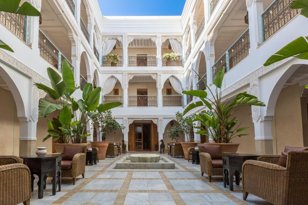 een lobby met een fontein, stoelen en planten bij Le Riad Villa Blanche in Agadir