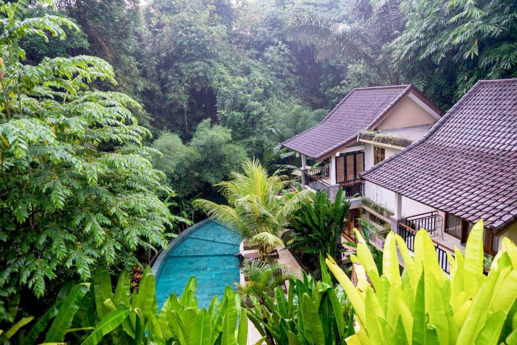 una casa con una piscina azul en medio de un bosque en Desak Putu Putera Cottages en Ubud