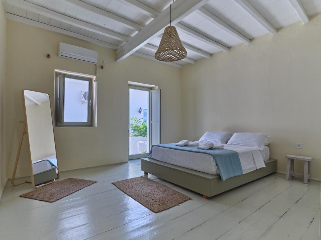 a white bedroom with a bed and a large window at Flair Naousa in Naousa