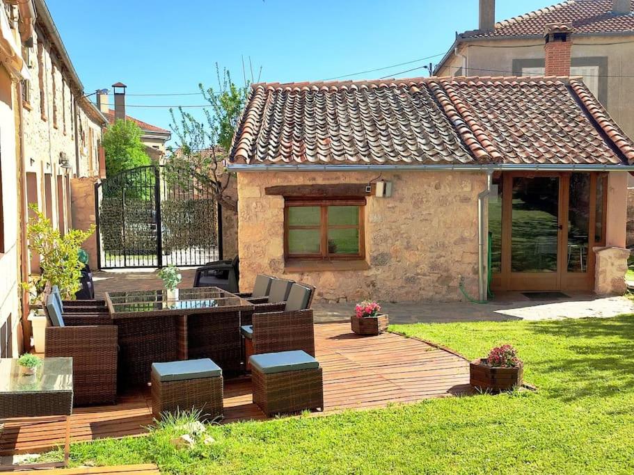 a wooden deck with chairs and a table in a yard at Casa Pinines in Torre Val de San Pedro