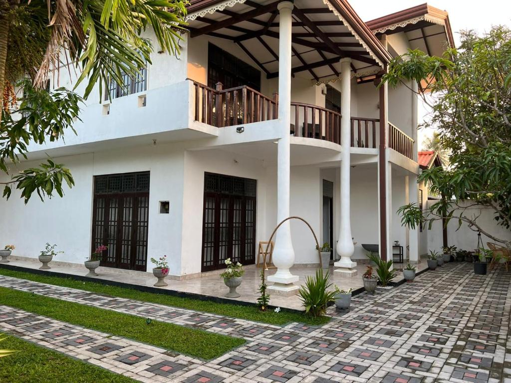 a white house with a balcony and a courtyard at Ja-Elas French Touch in Ja-Ela