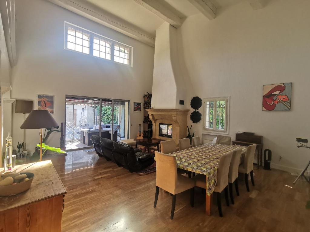 ein Wohnzimmer mit einem Tisch, Stühlen und einem Kamin in der Unterkunft Villa avec piscine et jacuzzi en bordure de forêt in Roquefort-les-Pins