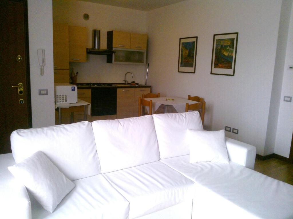 a white couch in a living room with a kitchen at Castelgabbiano in Castel Gabbiano