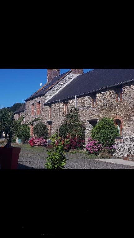un bâtiment en briques avec un toit noir et quelques fleurs dans l'établissement Gîtes des Archanges, à Macey