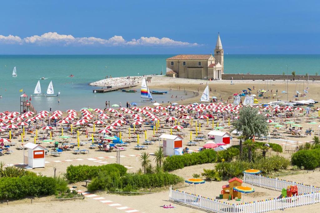 a beach with a lot of umbrellas and people on it at AMPIO BILOCALE Caorle LUNGOMARE LEVANTE in Caorle