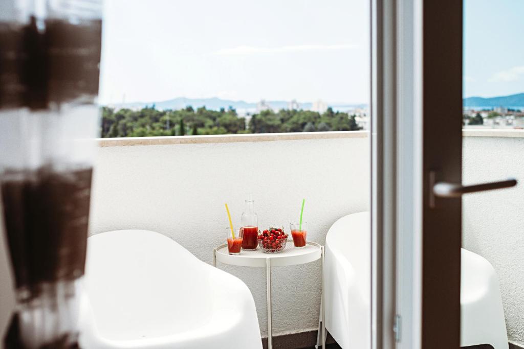 a balcony with two chairs and a table with drinks at Vista Zadar in Zadar