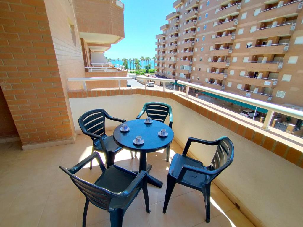 a table and chairs on a balcony with a view of a building at ACV - Vistamar II-1ª linea planta 3 sur in Oropesa del Mar
