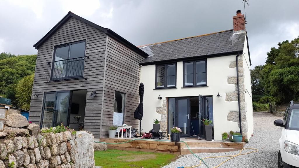 a white and black house with a stone wall at Luxurious property set in the heart of Cornwall with breathtaking views -Rhubarb Cottage in Helston