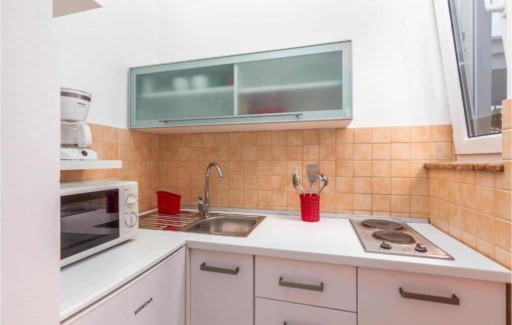a kitchen with a sink and a microwave at Nice Home In Njivice With Jacuzzi in Njivice