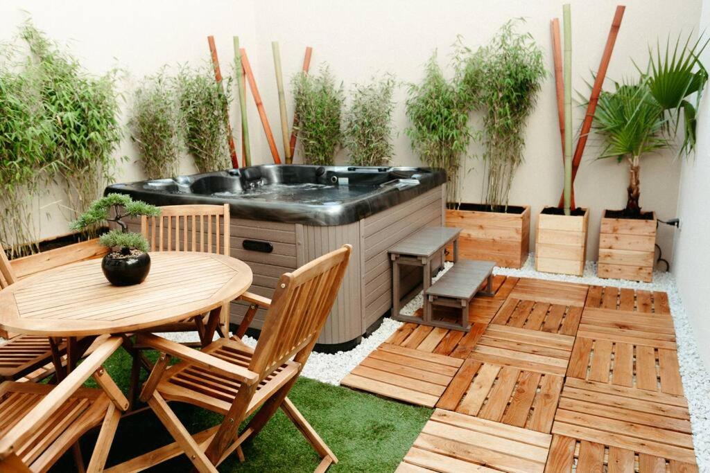 eine Terrasse mit einer Badewanne, einem Tisch und Stühlen in der Unterkunft La Villetta SPA -logement atypique in Mulhouse