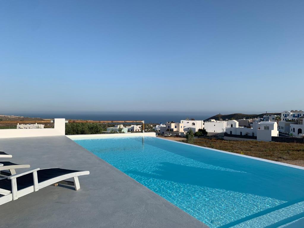 a pool with chairs and a view of the ocean at Acrothea Suites and Villas in Akrotiri