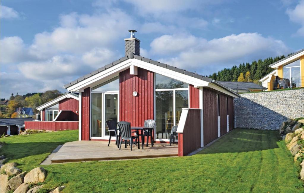 ein rotes Haus mit einer Terrasse und Stühlen auf einem Rasen in der Unterkunft St, Andreasberg, Haus 43 in Sankt Andreasberg