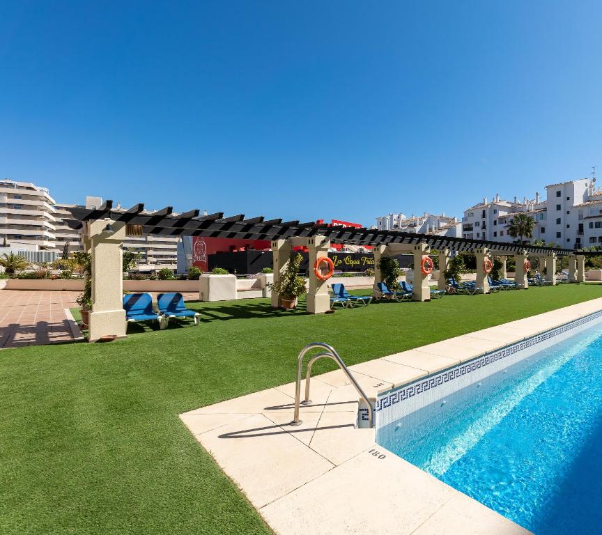 a swimming pool with green grass next to a building at Apartment in Puerto Banus with pool views and parking in Marbella