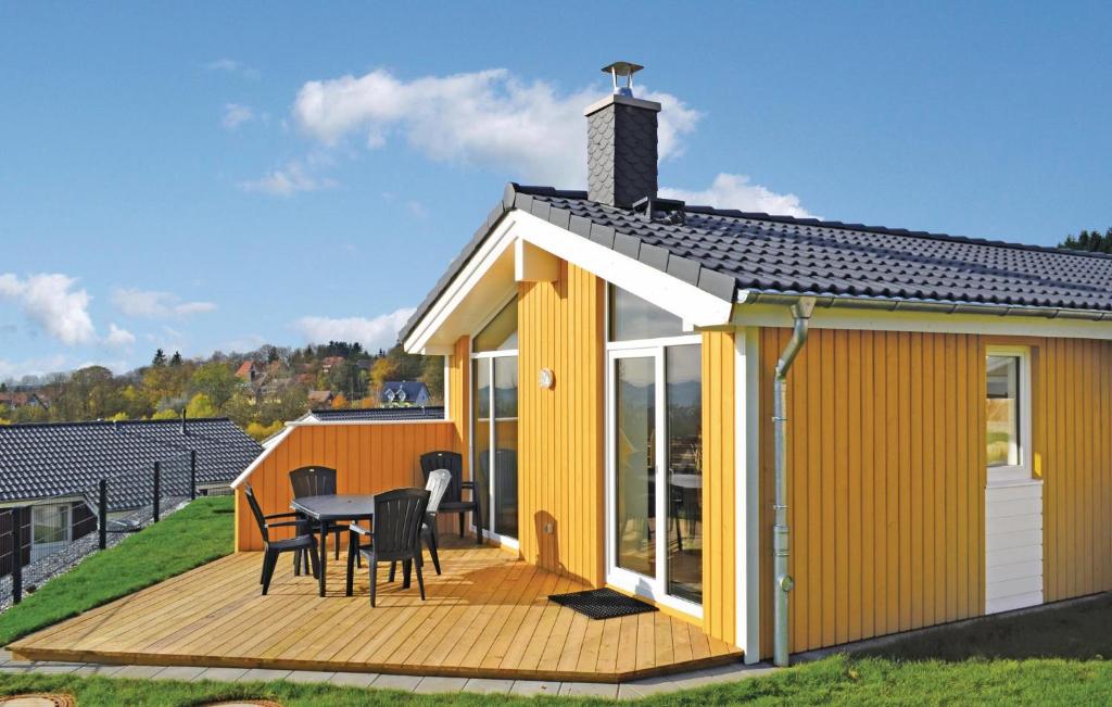 ein gelbes Haus mit einem Tisch und Stühlen auf einer Terrasse in der Unterkunft St, Andreasberg, Haus 44 in Sankt Andreasberg