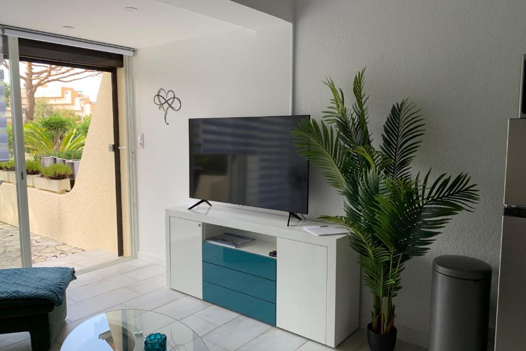 ein Wohnzimmer mit einem TV auf einem weißen Schrank in der Unterkunft Cap d'Agde Naturiste Hélio-village 95 in Cap d'Agde