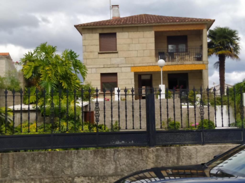 une maison avec une clôture devant elle dans l'établissement Apartamento en SANXENXO Planta alta, à Sanxenxo