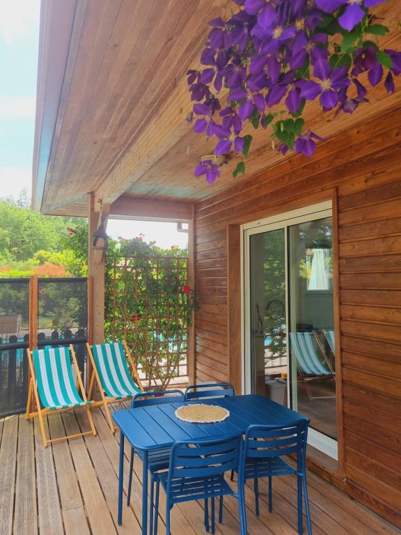 a blue table and chairs on a porch with purple flowers at Au calme, entre lac et océan in Vielle-Saint-Girons