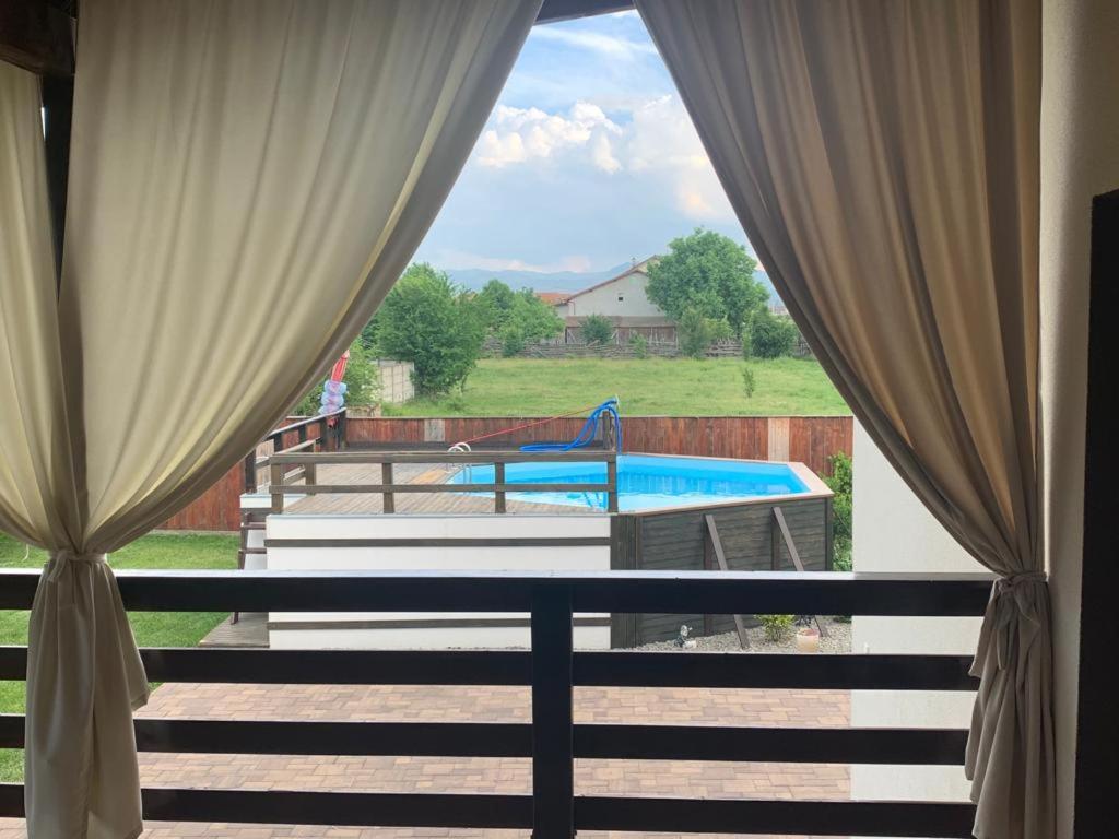 een raam met gordijnen en uitzicht op het zwembad bij Casa Deac in Sebeş
