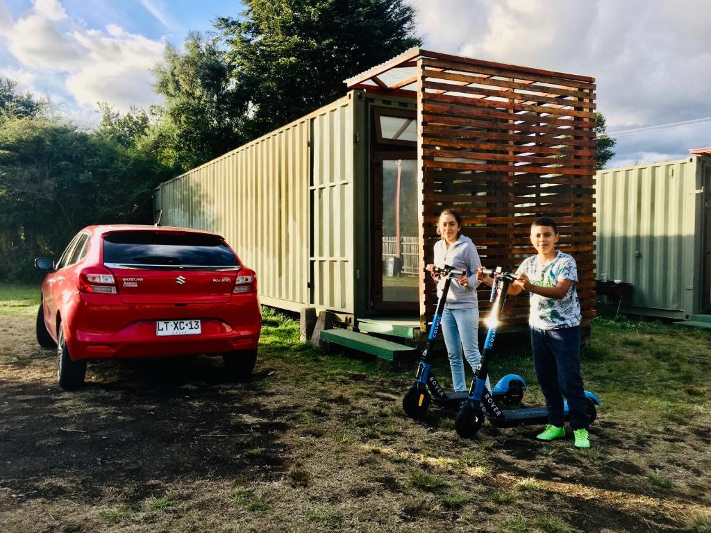 a man and a woman with scooters in front of a tiny house at Cabañas Habitainer in Pucón