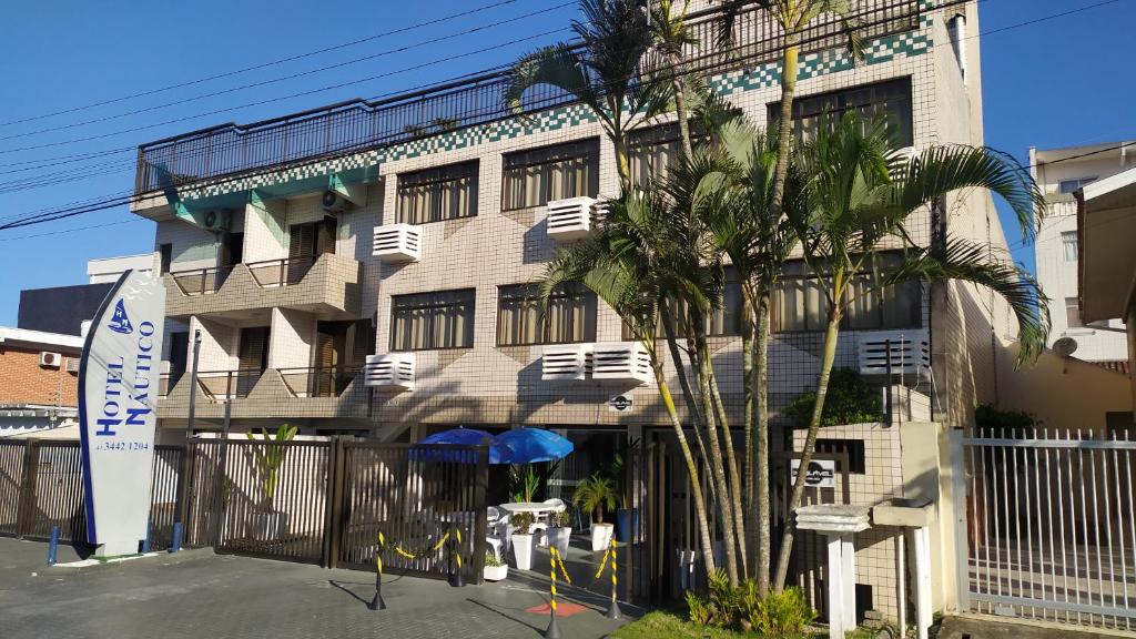 a building with a palm tree in front of it at Hotel Nautico in Guaratuba