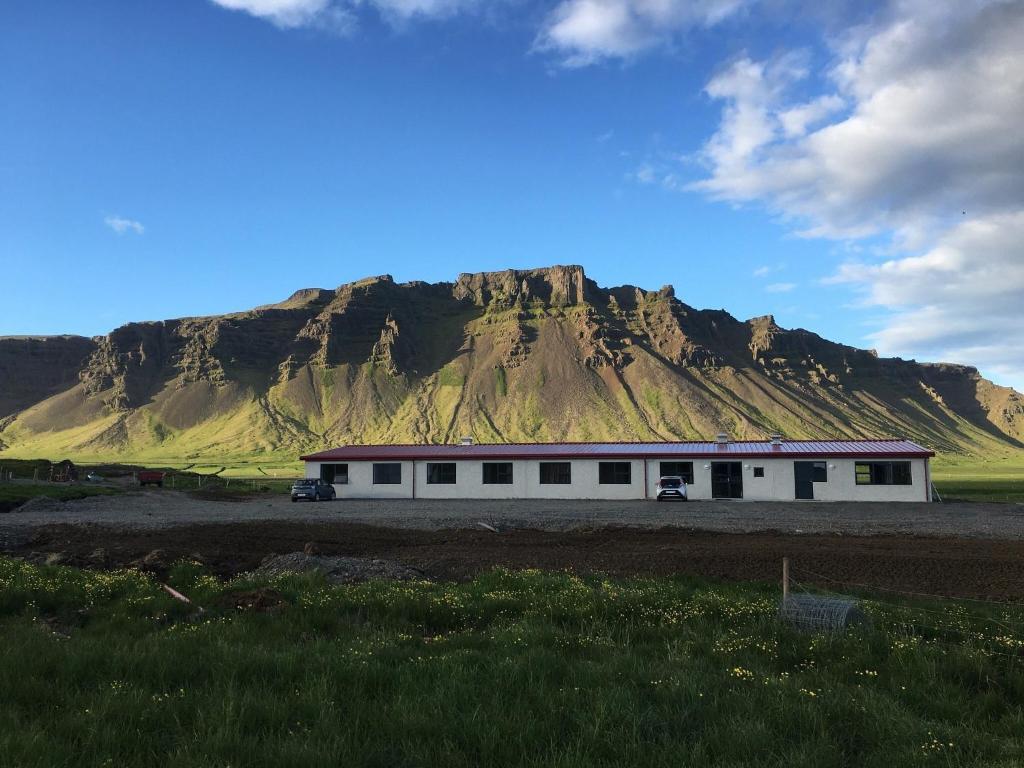 a white building with a mountain in the background at Vagnsstadir Guesthouse in Borgarhöfn