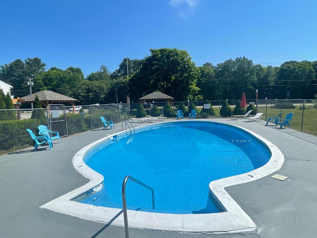 een groot zwembad met blauwe stoelen eromheen bij Aquastar Inn in Westerly