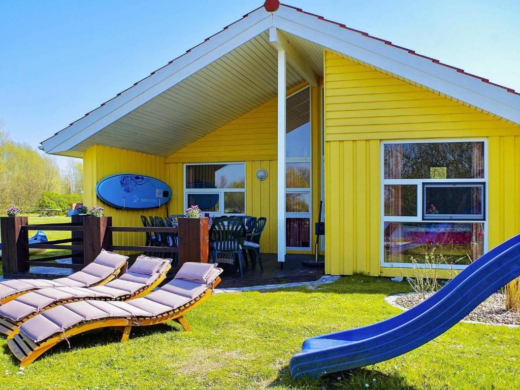 a yellow house with a slide and a playground at 12 person holiday home in Otterndorf in Otterndorf