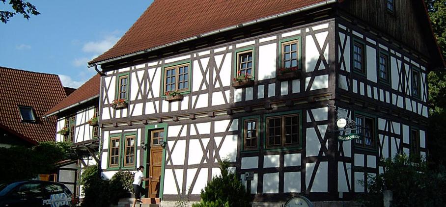 a white and black building with a brown roof at Ferienhaus Gesindestube Trusetal in Brotterode-Trusetal