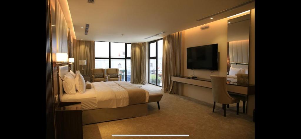 una camera d'albergo con letto, scrivania e TV di White House Apartments a Khamis Mushayt