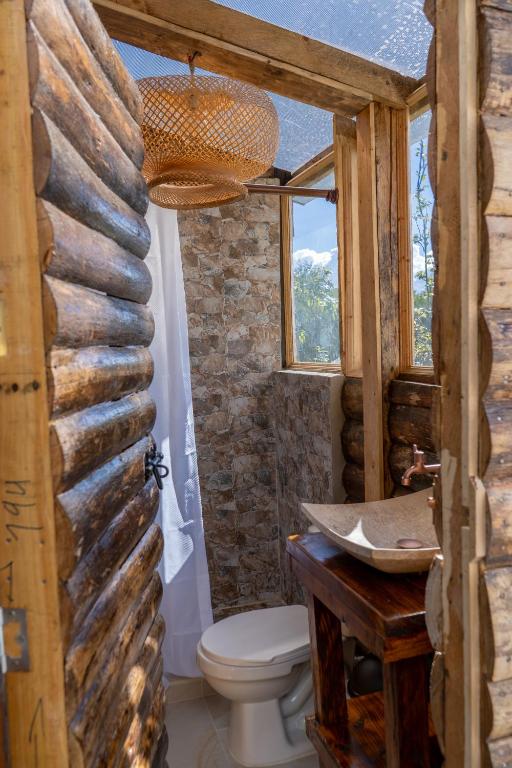 bagno con servizi igienici e parete in pietra di Alma de Campo Glamping - Laguna de Suesca a Suesca