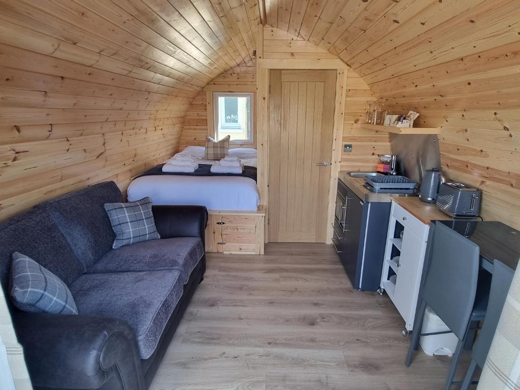 a room with a couch and a bed in a cabin at Caledonian Pod. In Caol, Fort William in Caol