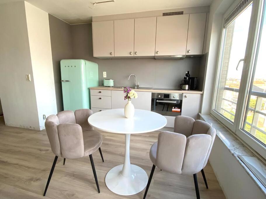 una cocina con una mesa blanca y 2 sillas y una mesa en Happy stay by Anaïs - 20m to beach, en De Panne