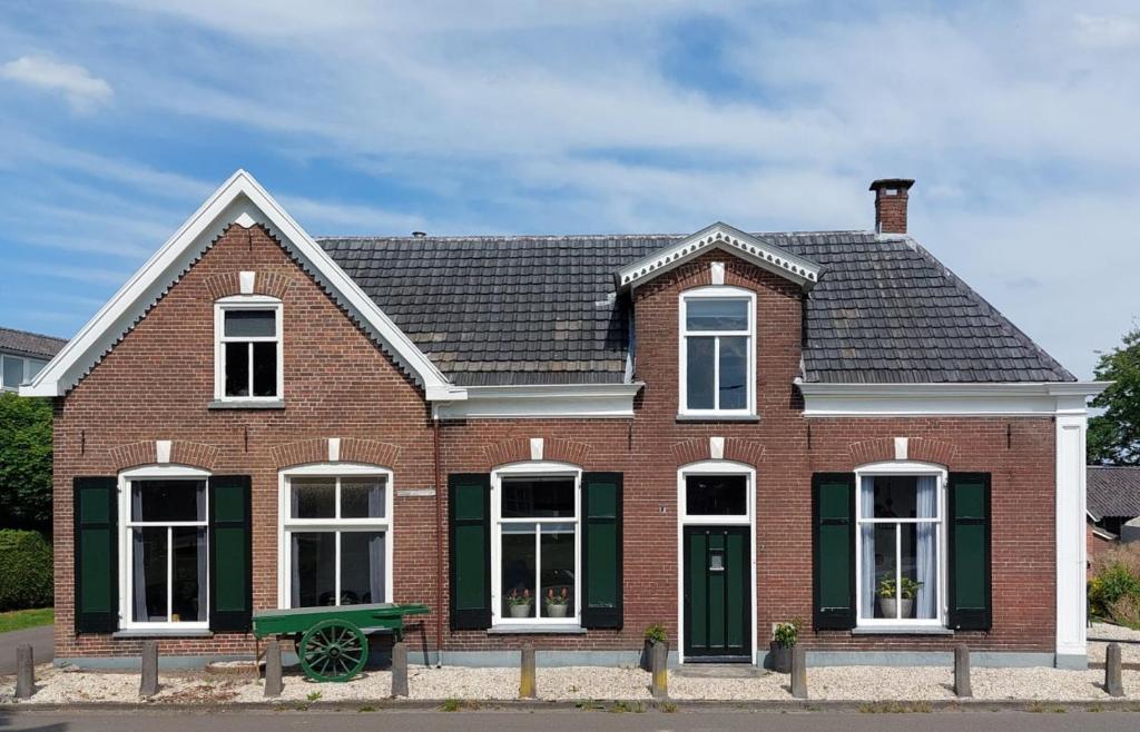 une maison en briques rouges avec des fenêtres blanches et des volets verts dans l'établissement Appartement Zonderland, à Wapenveld