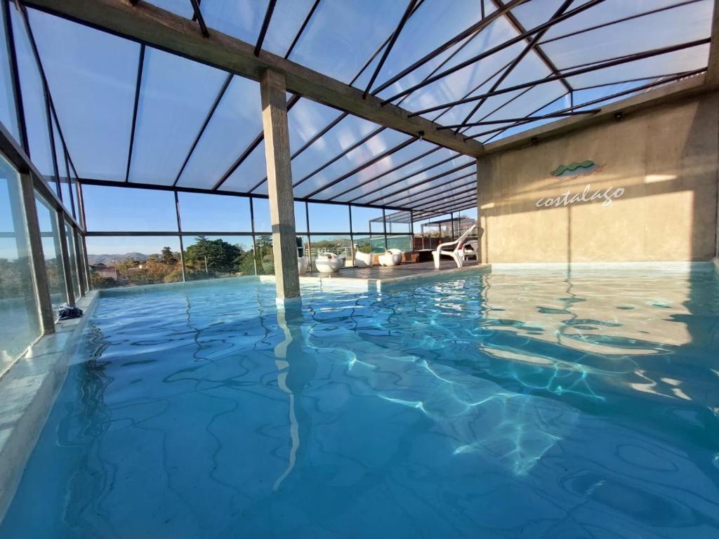 a large indoor swimming pool with a glass ceiling at Costalago Suites in Villa Carlos Paz