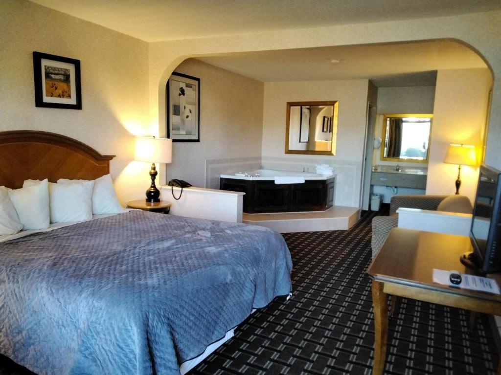 a hotel room with a bed and a bath tub at Quality Inn & Suites in Onley